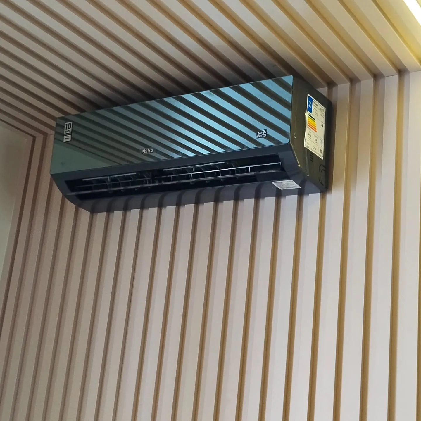Ar-condicionado split instalado pela Sena Climatização em sala com parede ripada, em Maringá